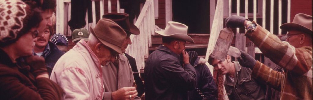 An auctioneer holds up two old bottles for sale