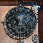 Wilson Place Door, a wooden door showing a wrought iron metal grill over a window.