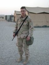 Image of a soldier in front of beige colored tents