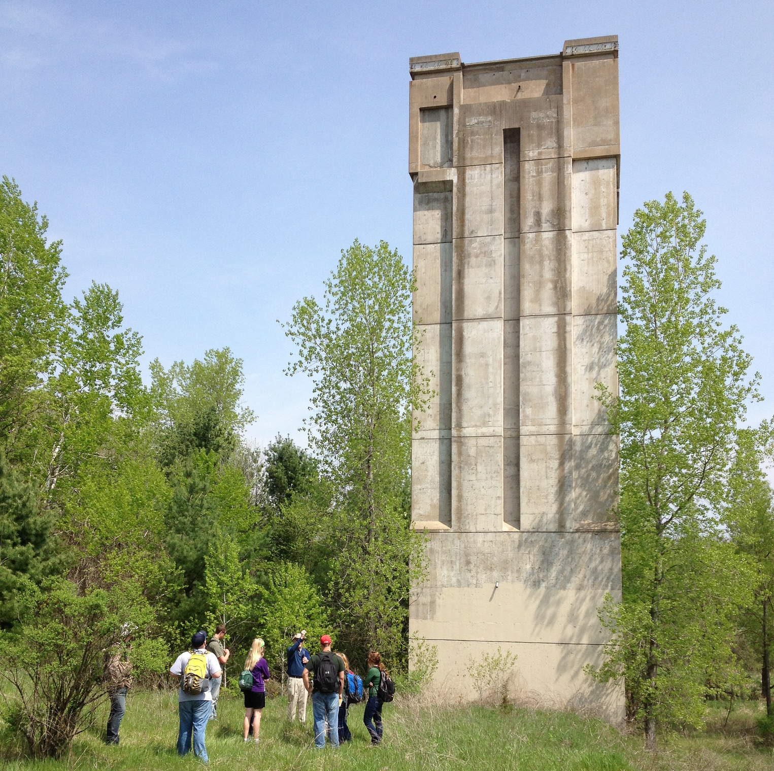 A picture of the Kickapoo Valley Reserve dam tower showing a concrete tower rising nearly 100 feet above a grassy lawn
