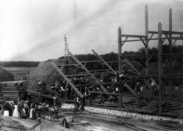 a black and white image of a community barn raising rom 1891