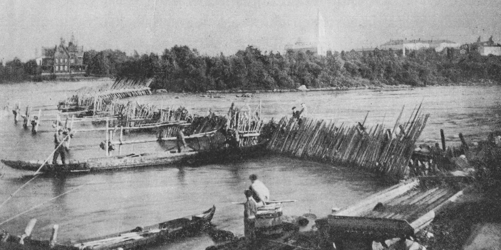 Men in boats fishing beside a wooden weir