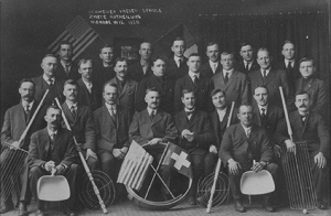 A group photo showing a gathering of men behind an American and a Swiss flag