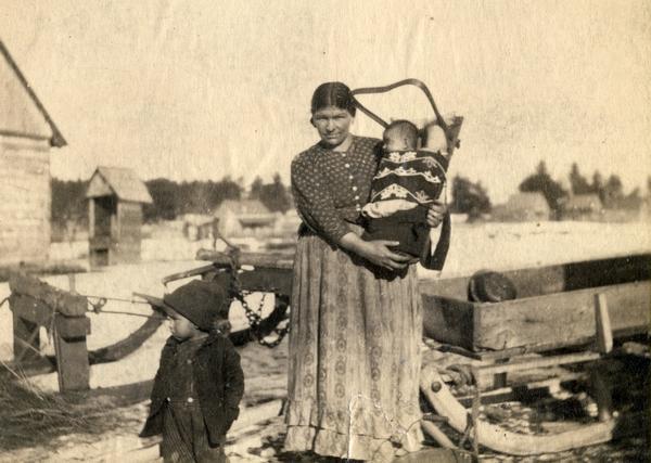 an Ojibwe woman holding a baby in a cradleboard