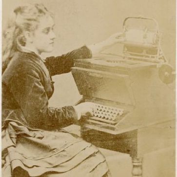 Christopher Sholes' daughter Lillian sitting at a prototype typewriter.